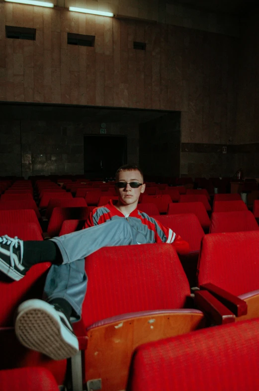 a man sitting in a theater on top of red seats