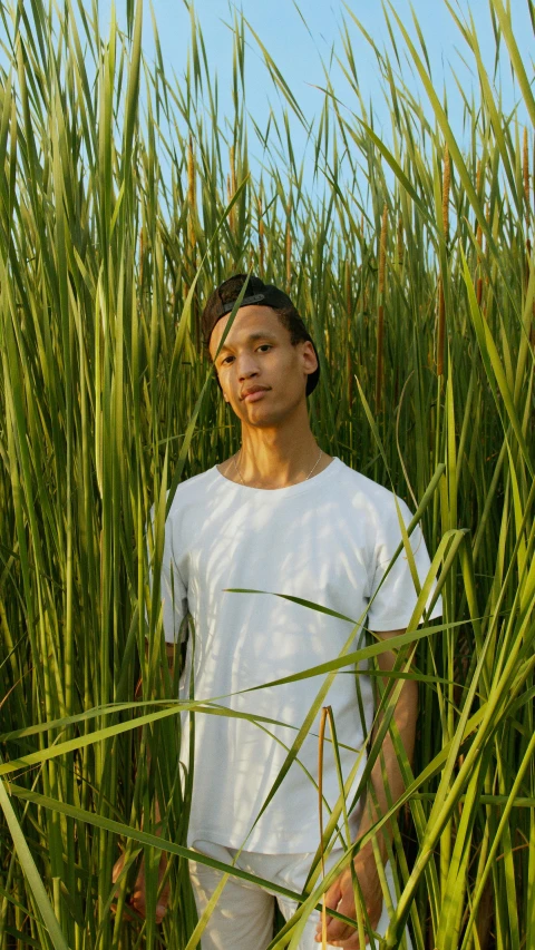 an asian man wearing white poses in tall grass