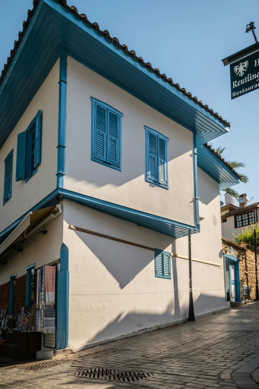 a white and blue building with shutters on the top of it