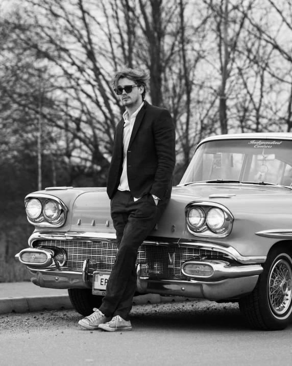 a black and white po of a man leaning on a car