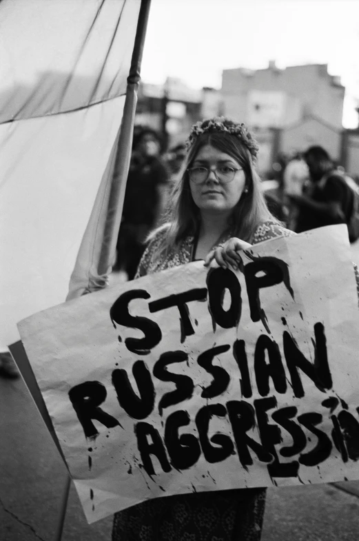 black and white pograph of woman holding protest sign with stop russian aggression message