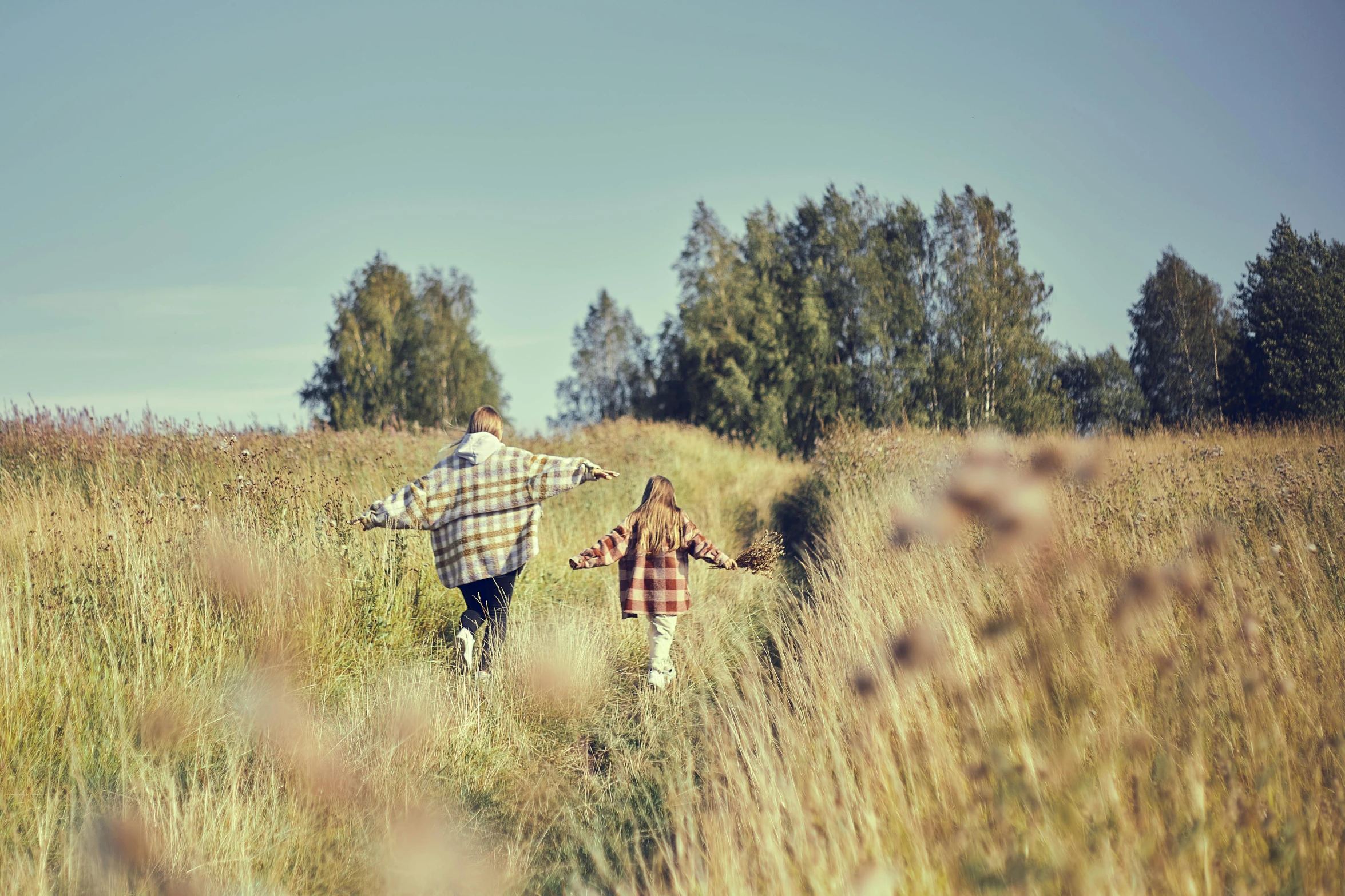 two people walk down a long grassy path