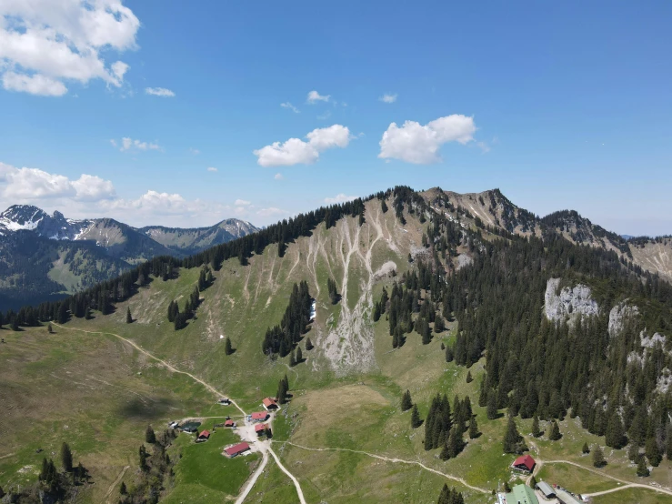 the landscape in this po is gorgeous and shows a mountain landscape with hills, lakes and houses, with blue skies