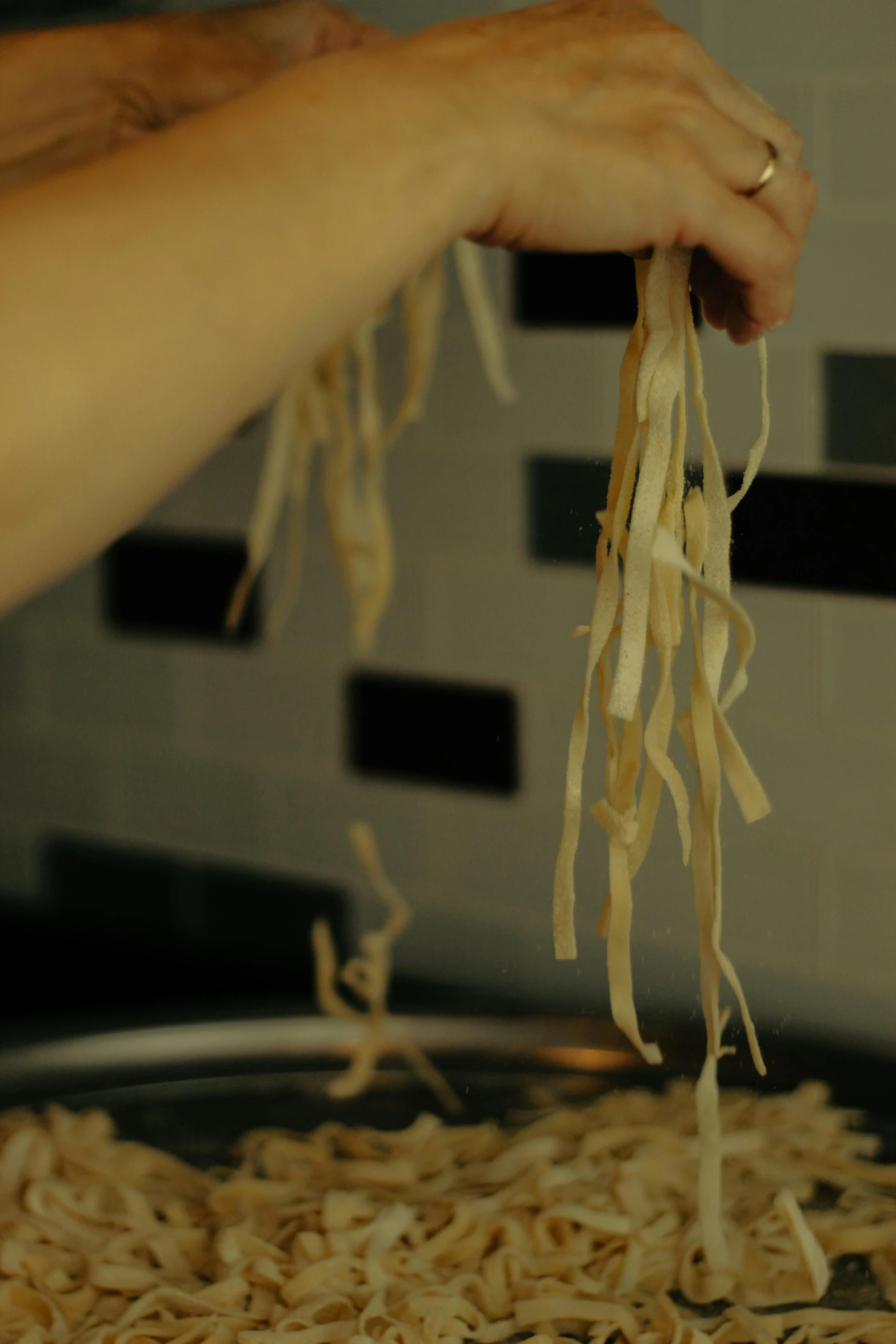 a person holding up noodles from a pan of noodles