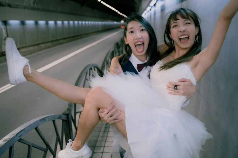 two women dressed up for an anniversary or wedding, one is carrying the other's leg