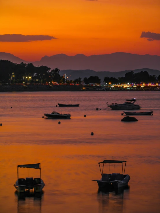 four small boats floating in the water at sunset