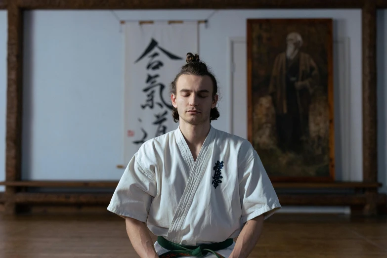 a man in white is sitting in front of some paintings