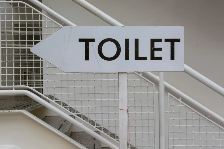 a white street sign with black writing stating toilet