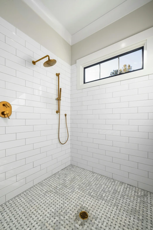the shower has a gold shower head and shower rod