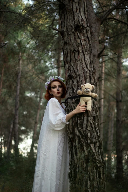 a woman in an old fashioned gown holding a teddy bear