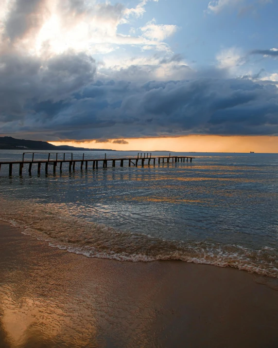 a long pier stretching into the ocean on a cloudy day