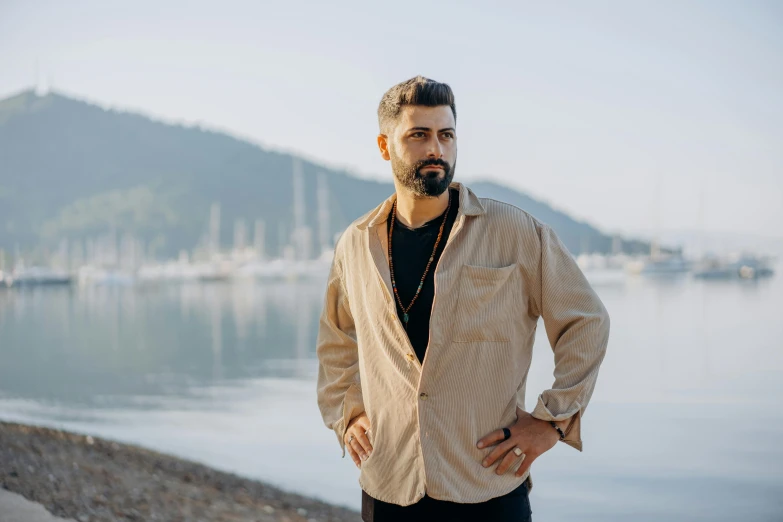 man looking down standing on the shore with boats in the background