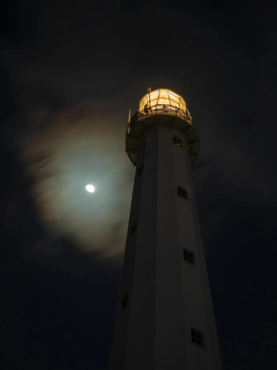 an image of a light tower with the moon in background