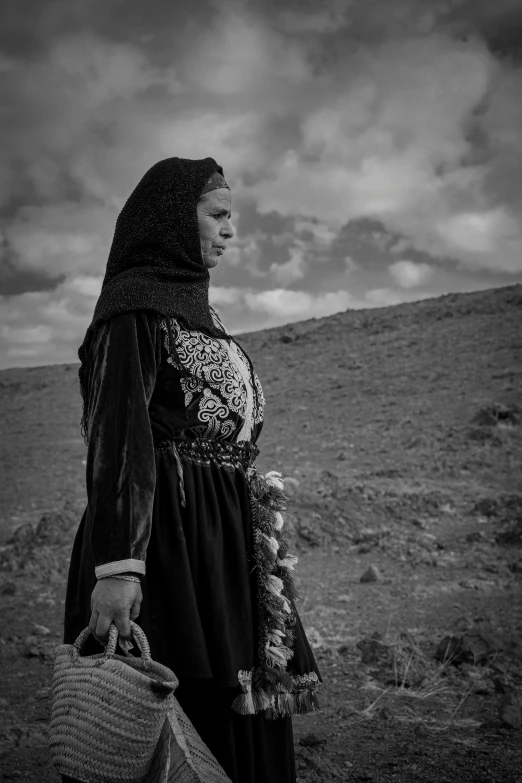 a woman is standing in front of a hill