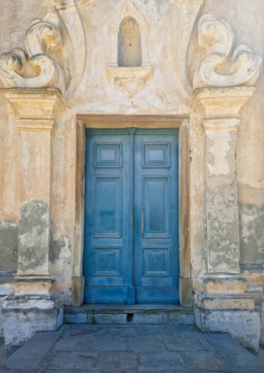 a blue doorway leading to two statues on the side of a wall