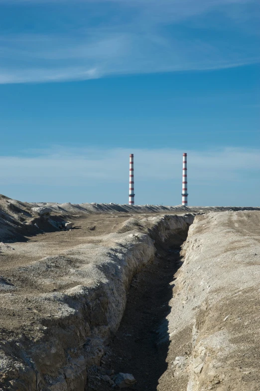 two tall pipes stand near the sandy ground