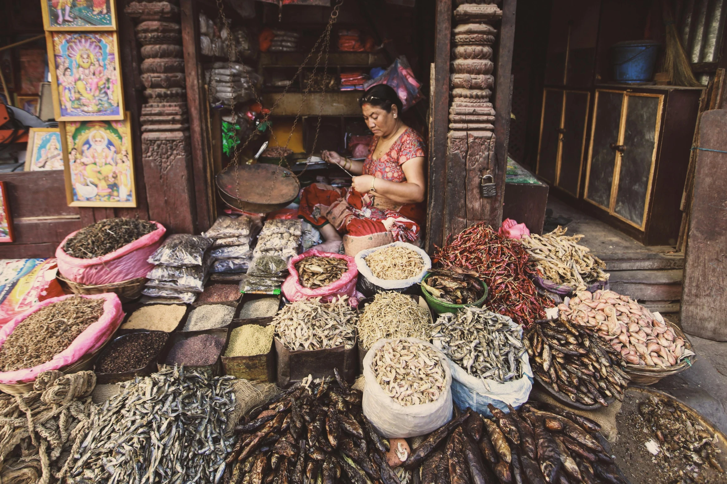 an asian woman sitting behind piles of dried goods