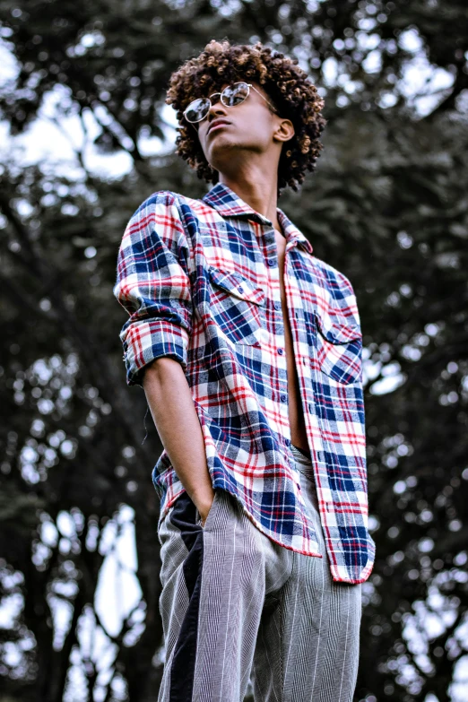 a person with dreadlocks standing near trees