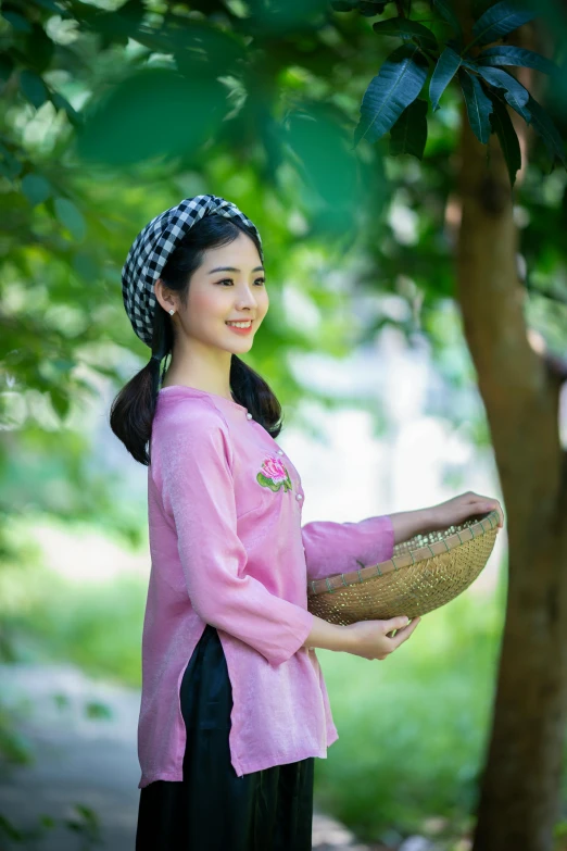 a woman holds a basket beneath a tree