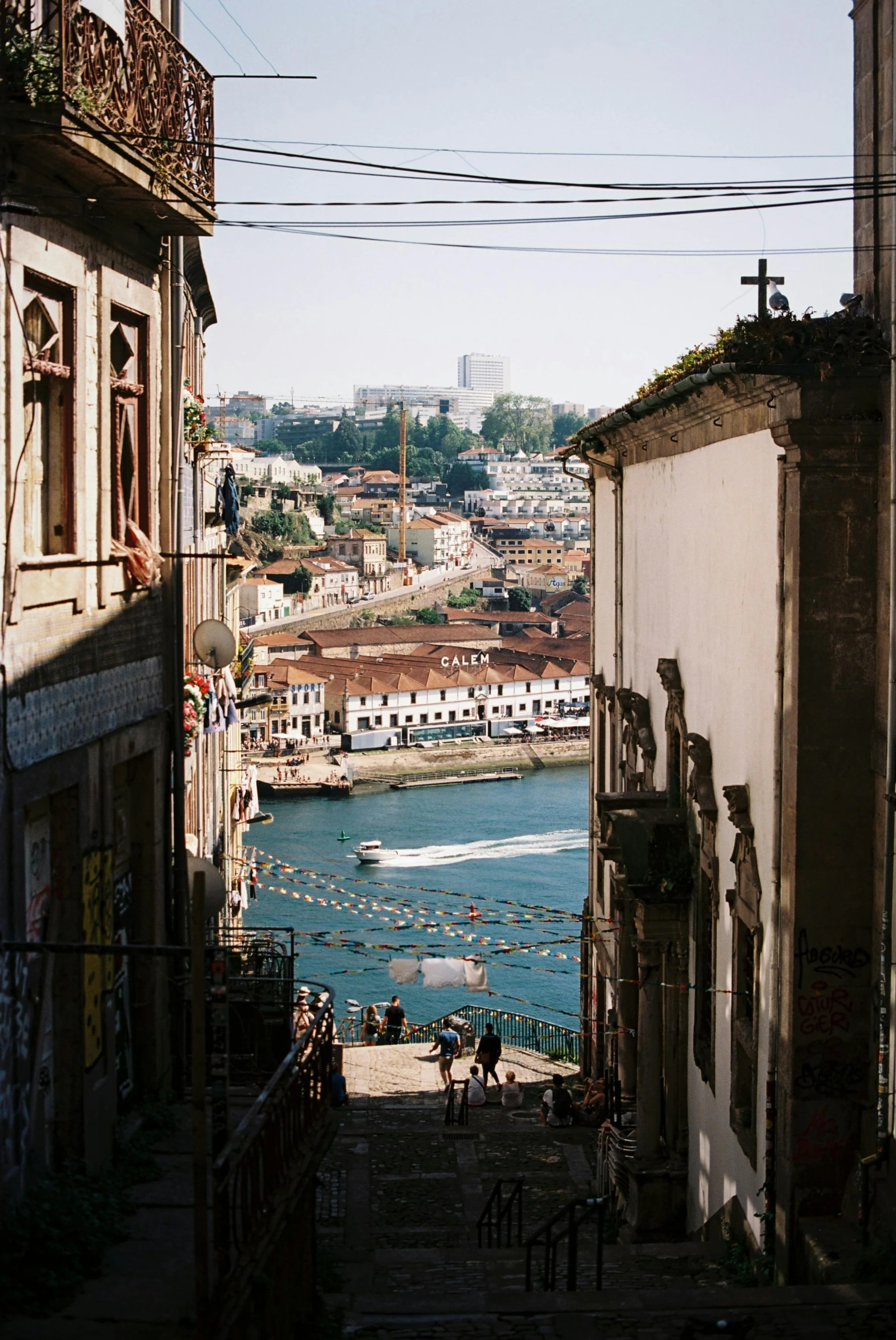 some buildings and people a river and wires