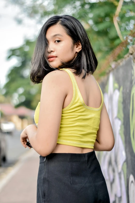 woman standing by a wall in a yellow top