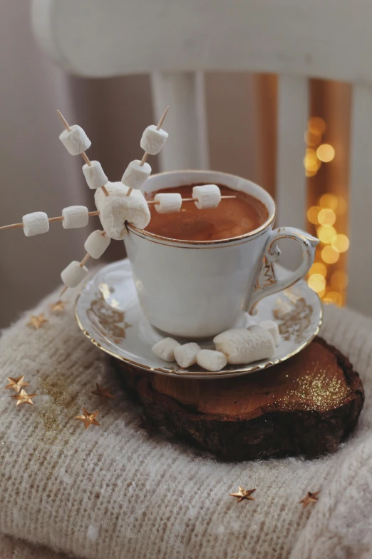 there is coffee cup with marshmallow sticks in the cup