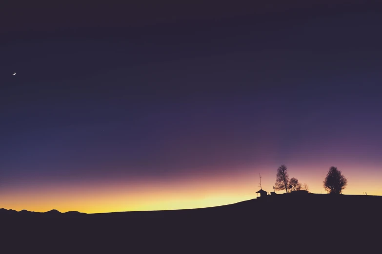 the sky and the moon are seen over a hill