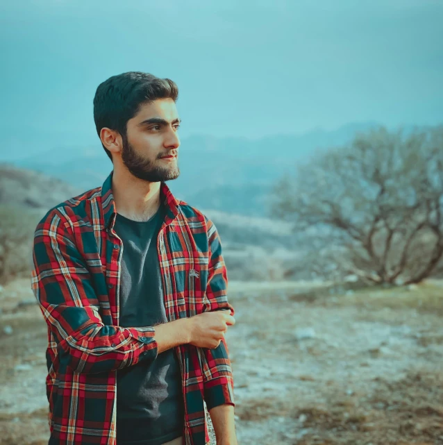 a man in plaid shirt standing on top of dry grass