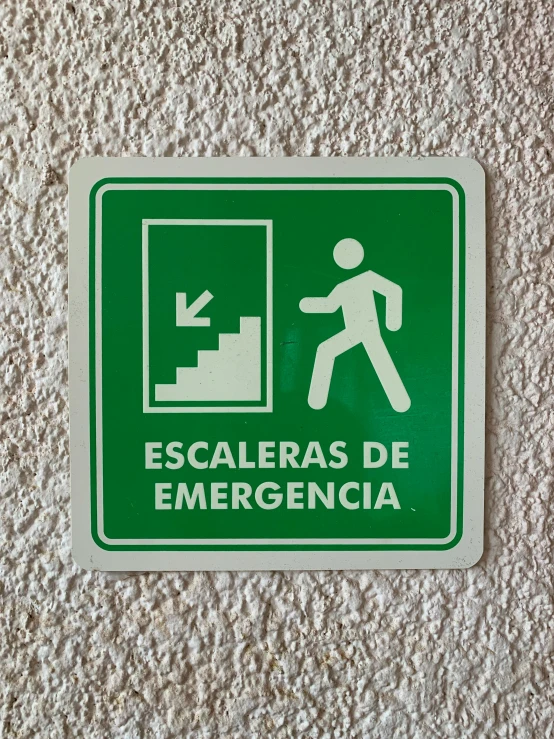 a green sign points the way in spanish and the man walks