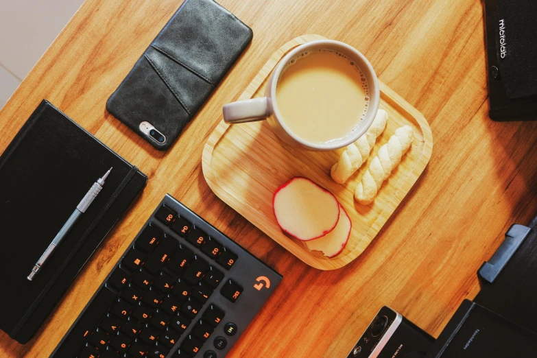 a coffee mug, apple slices, pen, and notebook on a desk