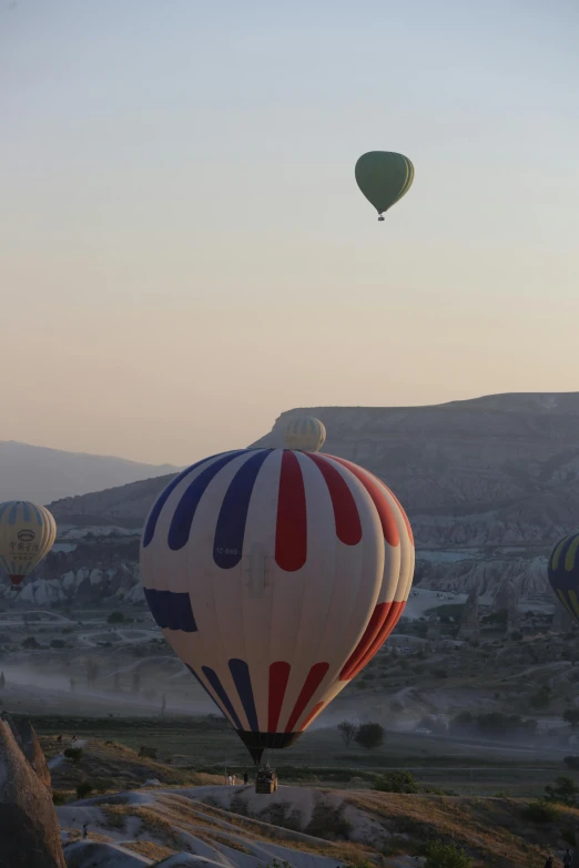 several  air balloons are flying above some mountains