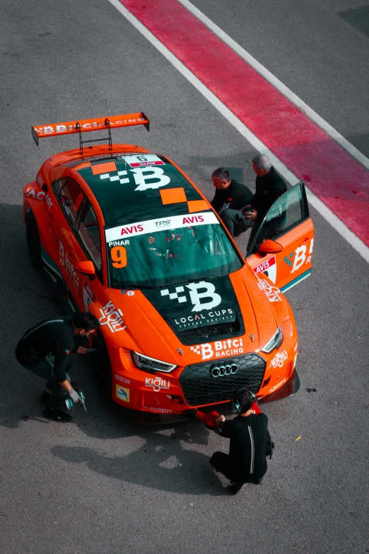 an orange racing car is being checked out by the crew