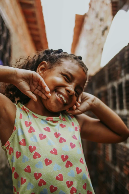 a little girl smiling for the camera while holding her hands on her shoulder