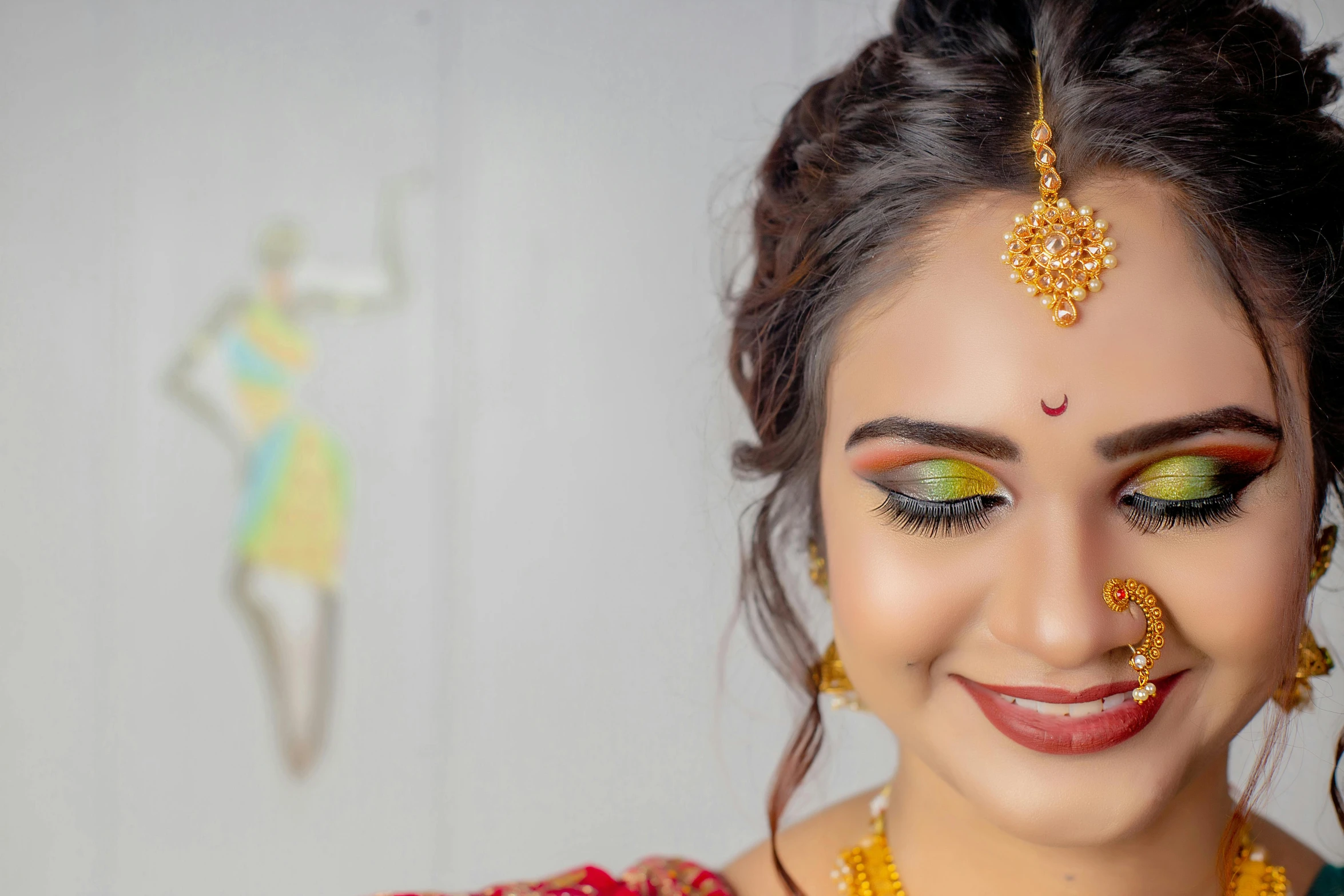 an indian woman wearing gold jewelry and a green eyeshade