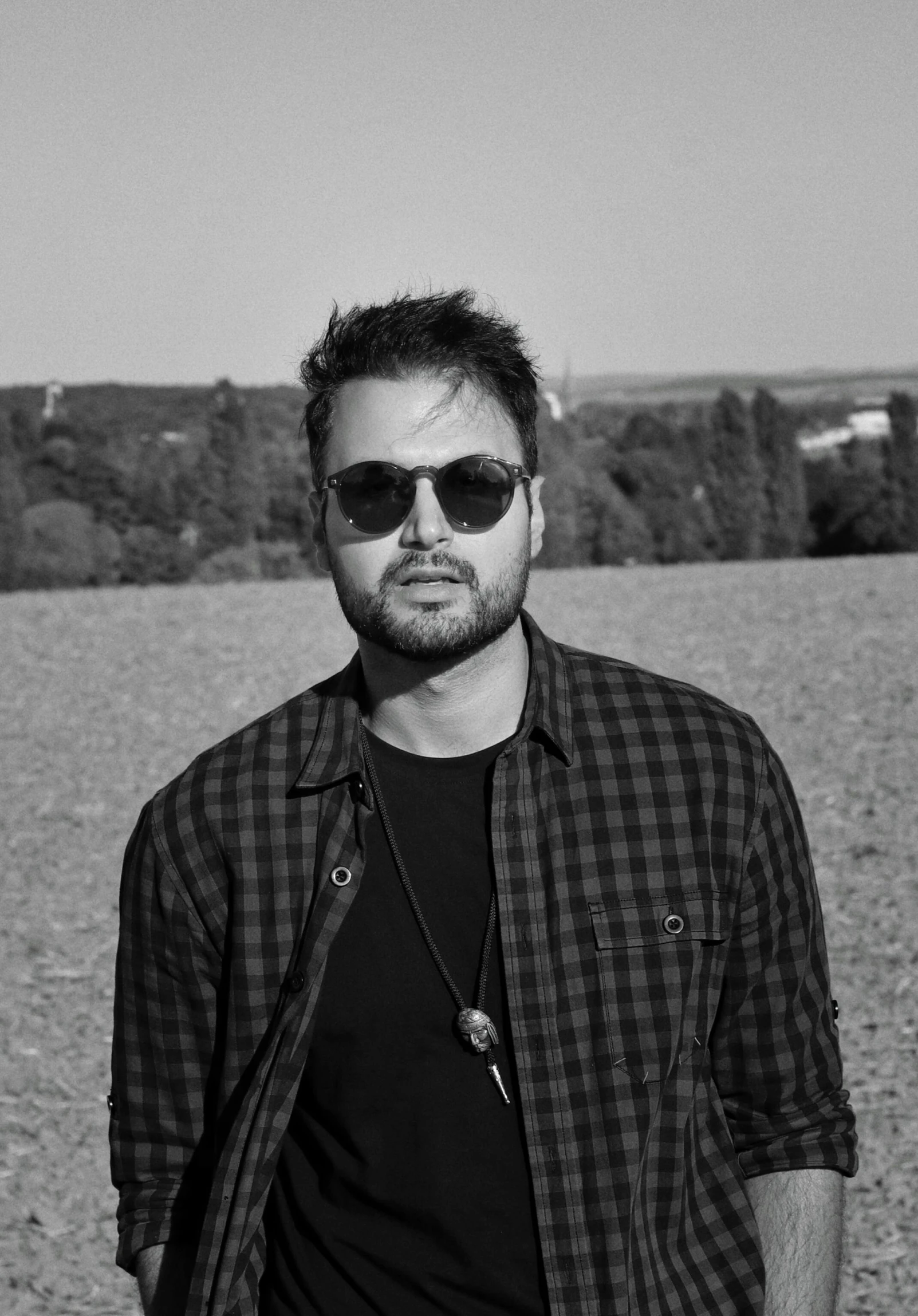 black and white po of man with sunglasses on at beach