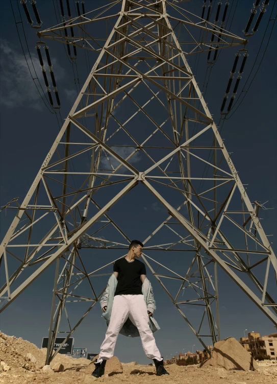 a man standing underneath an electric tower with his hand on his hips