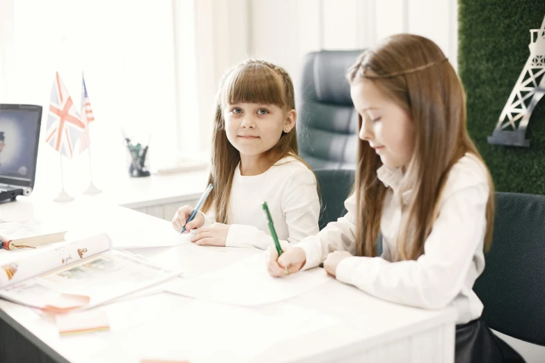 two s sitting at desk in front of computers