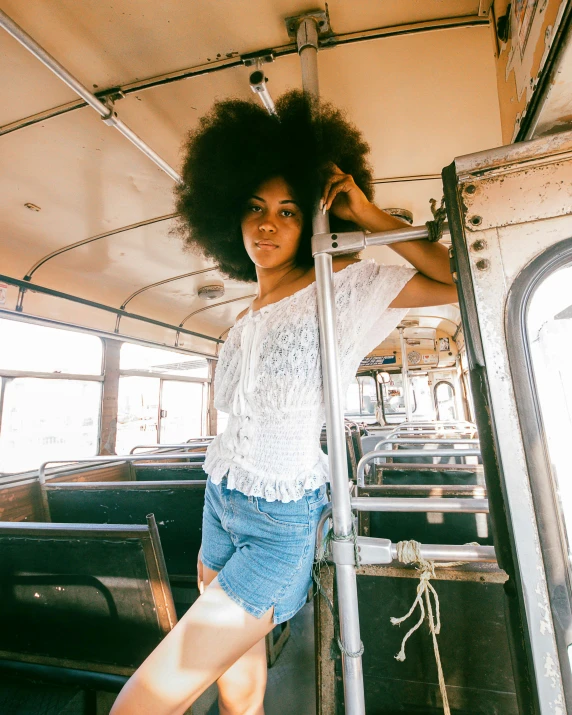 a young woman stands on a trolley with her hand on the railing