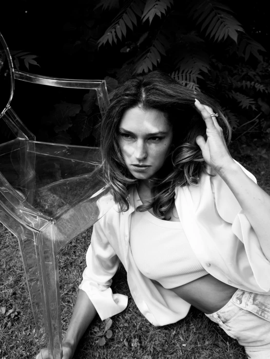 a young woman sits on the ground with a glass box around her