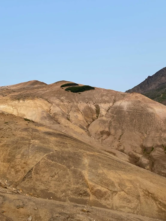 an old airplane flying above a hill with a sky background