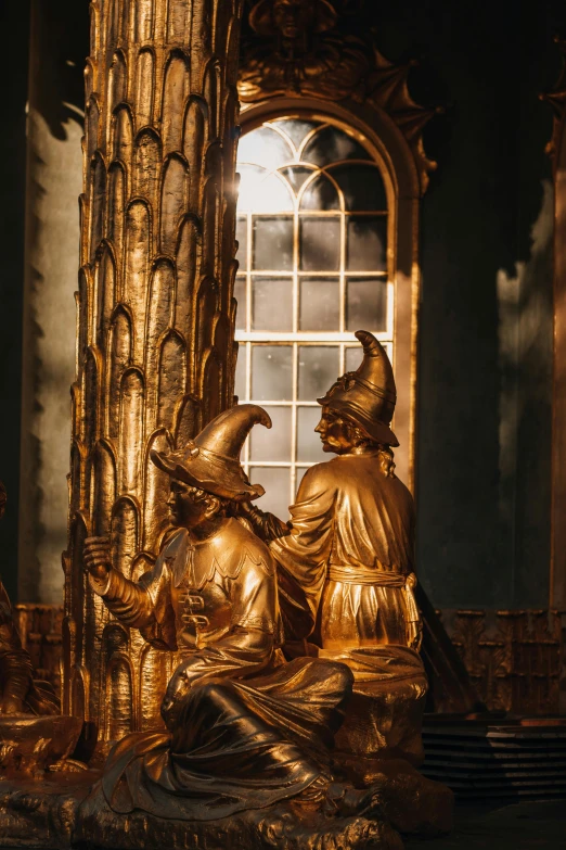 some golden statues sit on a table next to a window