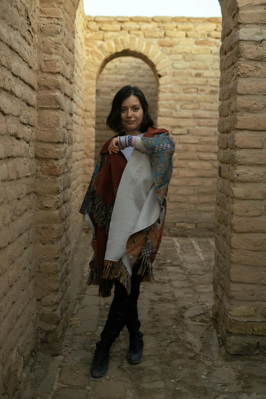 a woman is standing in an alley holding a scarf