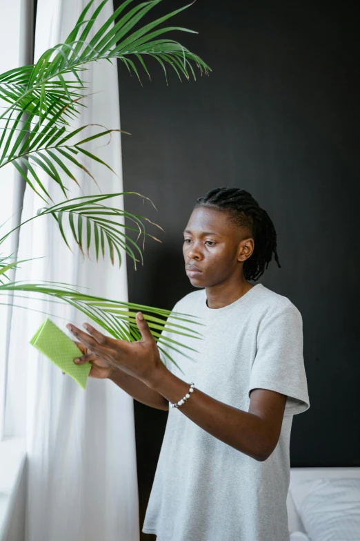 a woman in white shirt holding up a green plant