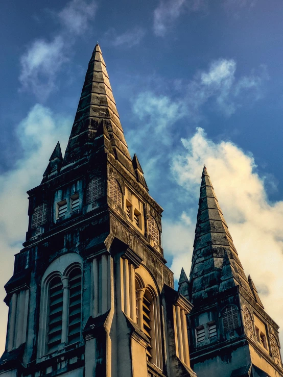 two towers of an old building with clouds in the background