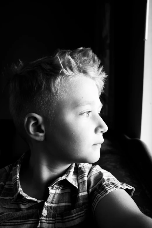 boy looking out of window on black and white image