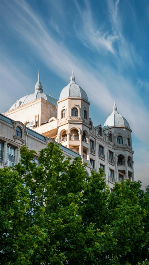 a building with two roof top domes and green trees