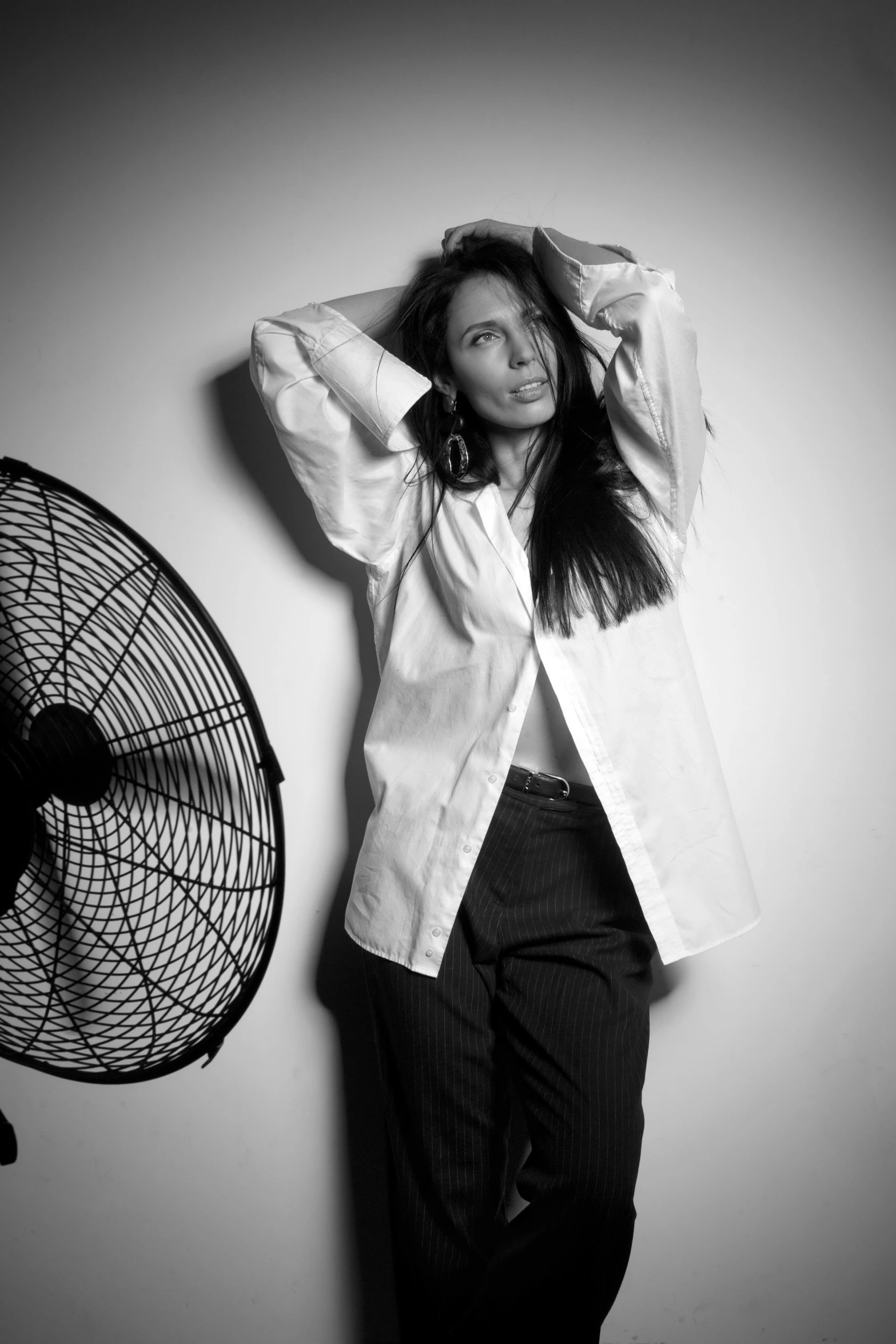 a woman standing in front of a fan in the corner