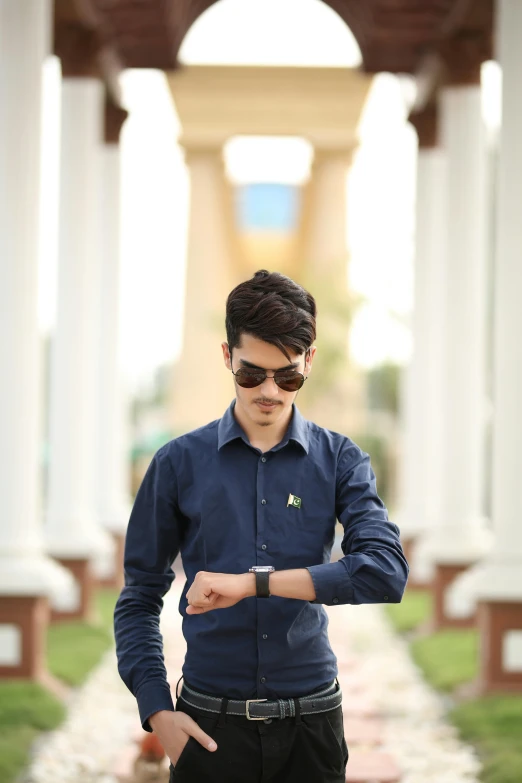 young man wearing sunglasses and making hand sign at the end of a walkway