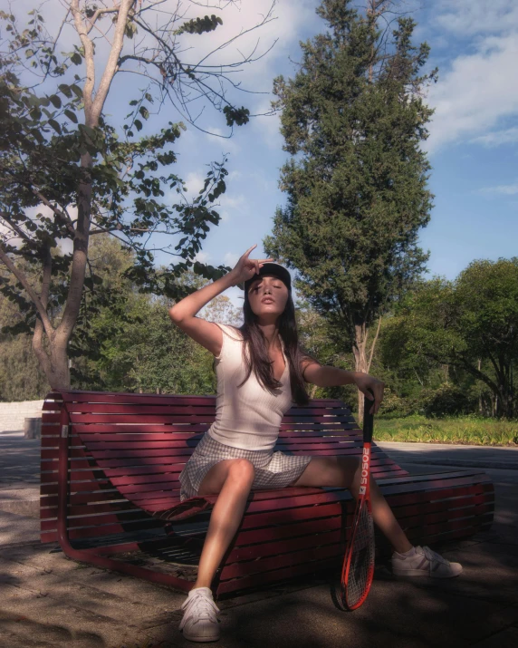 a woman in white dress sitting on bench with tennis racket