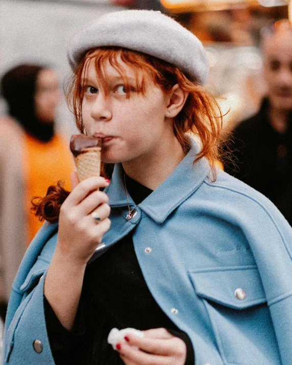 a woman is outside eating a chocolate ice cream sandwich